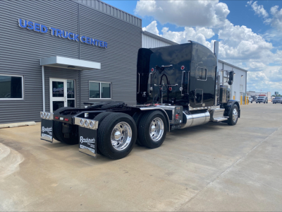 Peterbilt 389 truck tractor rear view showing triple axles and fifth wheel at a used truck center.