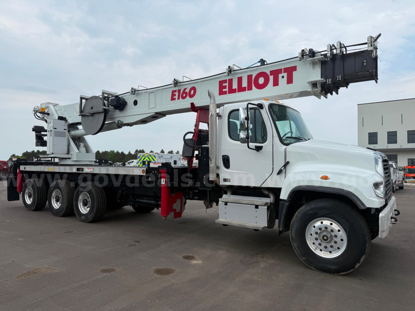 Boom truck shows E160 Elliott crane with white cab and extended boom in Kenworth chassis.