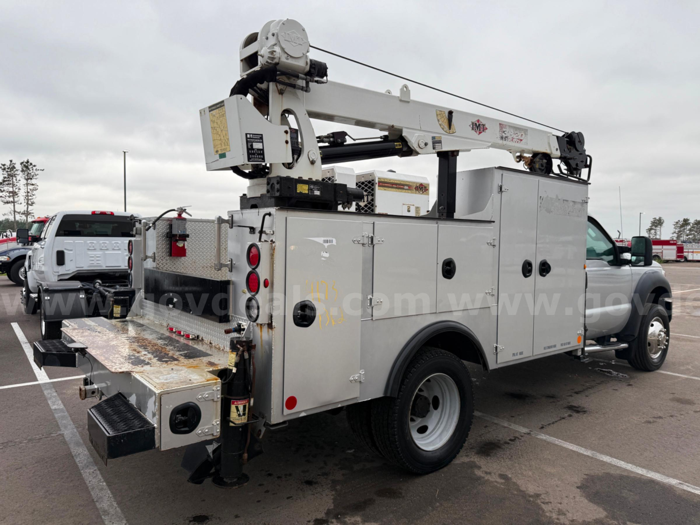 Ford F-550 service/util truck with utility bed and ladder boom rear view showing service compartments