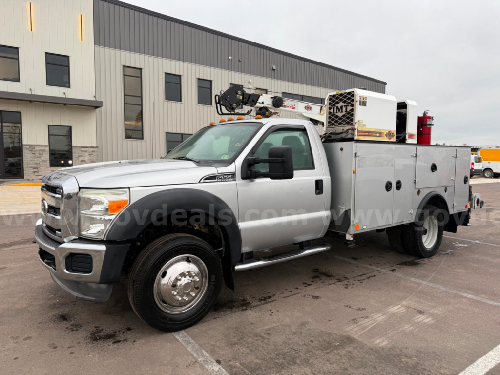 Ford F-550 service/utility truck with utility bed, crane, and tool compartments in a parking lot.