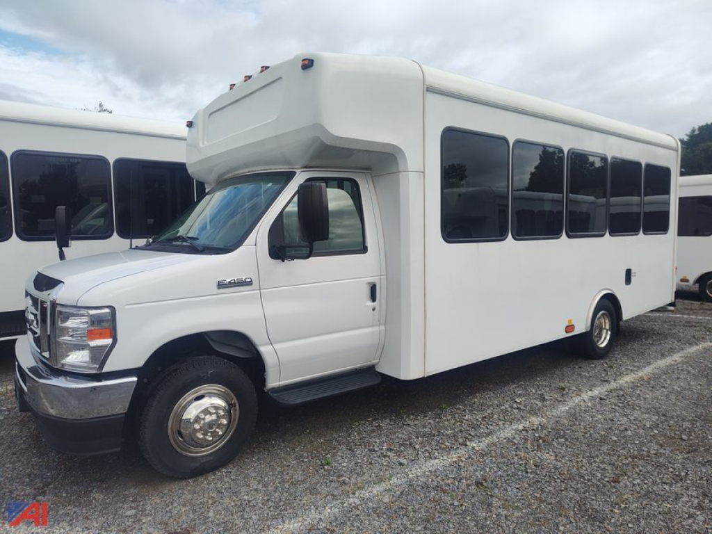 Ford E-450 wheelchair bus in white with large passenger windows and blank side panels, front cab with wheelchair lift housing over cab roof.