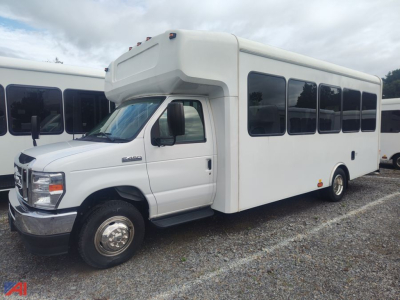 Ford E-450 wheelchair bus in white with large passenger windows and blank side panels, front cab with wheelchair lift housing over cab roof.
