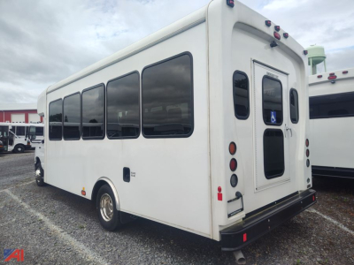 Bus rear and driver's side showing large windows, wheelchair lift door, and vinyl exterior on a used 2026 Ford E450 HLE Coach Wheelchair Bus.