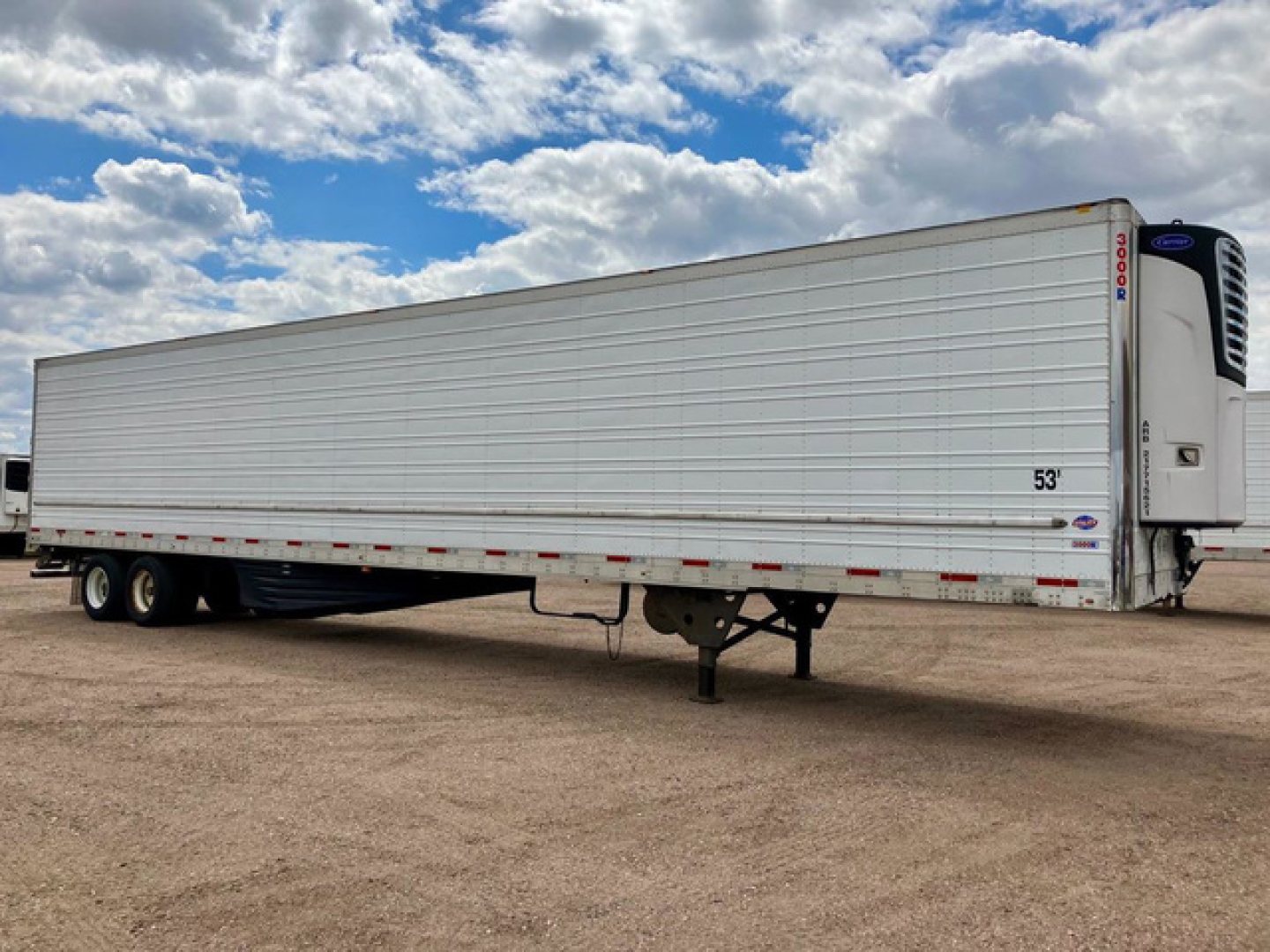 Refrigerated trailer in-line axle configuration with white reefer unit at front showing Thermo King or similar cooling unit and side door, blank silver body, in a dirt lot.