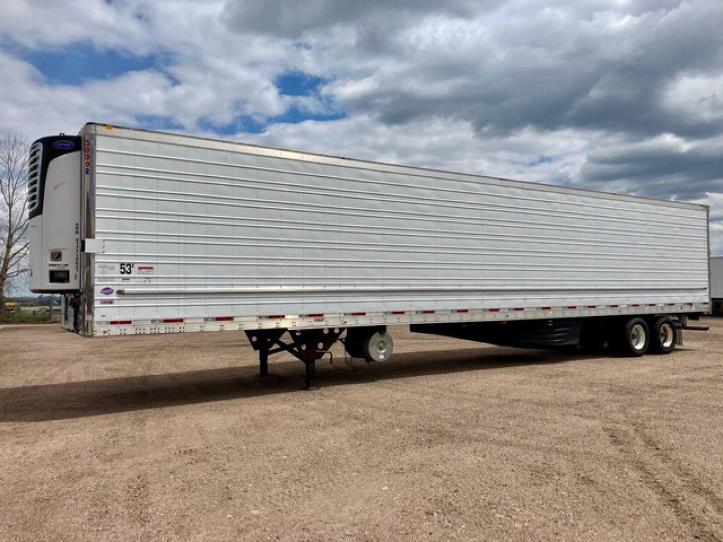 Trailer side view of a 53 ft refrigerated trailer with Thermo King unit at front, aluminum corrugated siding, DOT reflective tape, landing gear and dual rear axles.