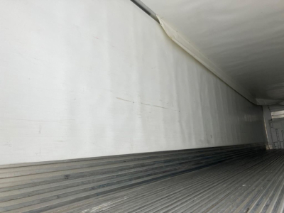 Inside view of a refrigerated trailer cargo area with ribbed floor and smooth side walls.