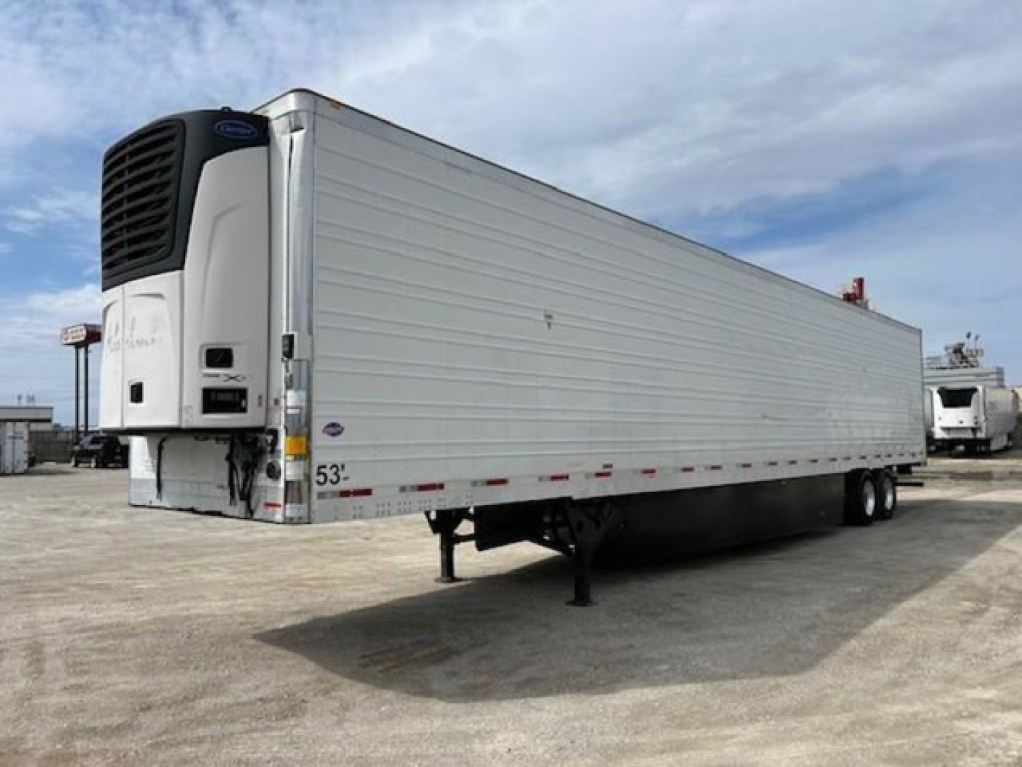 Trailer showing a refrigerated utility trailer with a front refrigeration unit and a raised landing gear. Side of trailer has 53' length markings and small stickers near the front.