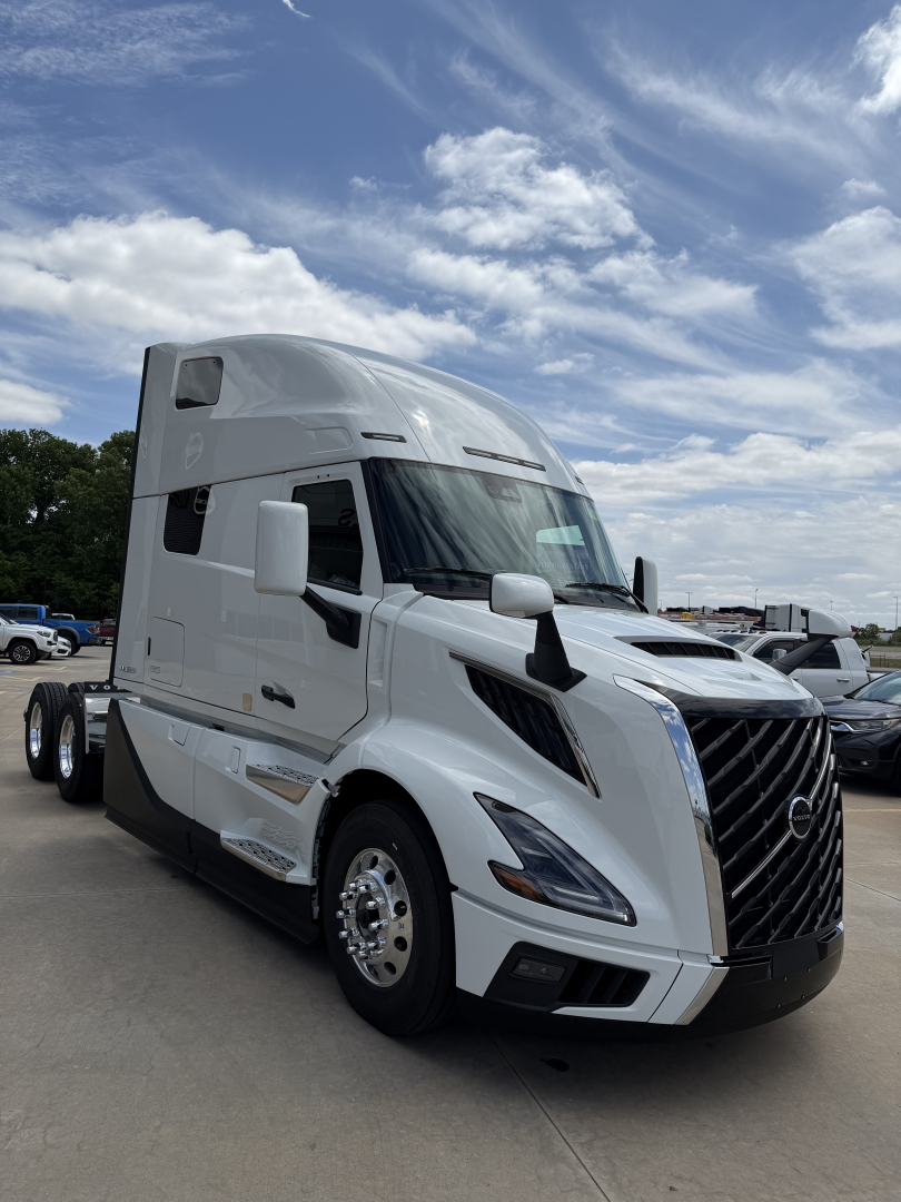 Volvo VNL64T860 tractor-trailer cab in white, side view showing aerodynamic mirrors, sleeper cab, chrome grille, and dual rear axles.