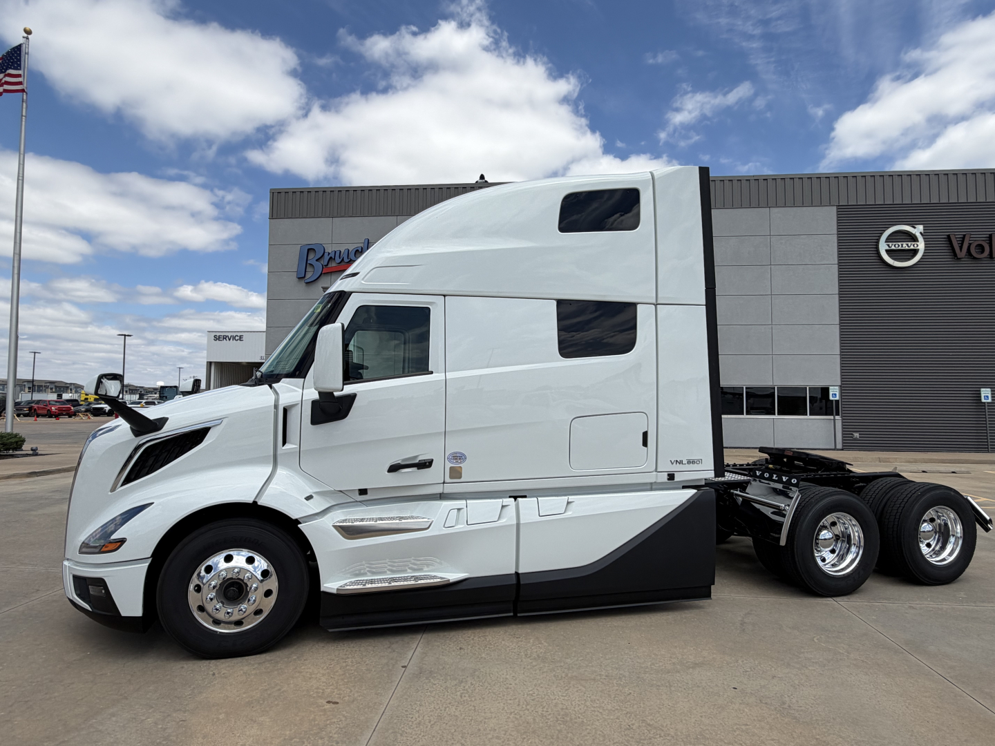 Volvo VNL64T860 tractor in white exterior with sleeper cab, side view showing wheel hubs, aerodynamic mirrors, and chassis; stock number 72555 and dealership backdrop.