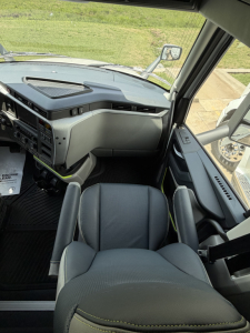 Cab interior of a 2027 Volvo VNL64T860 showing steering wheel area, dashboard, and driver seat with light gray upholstery.