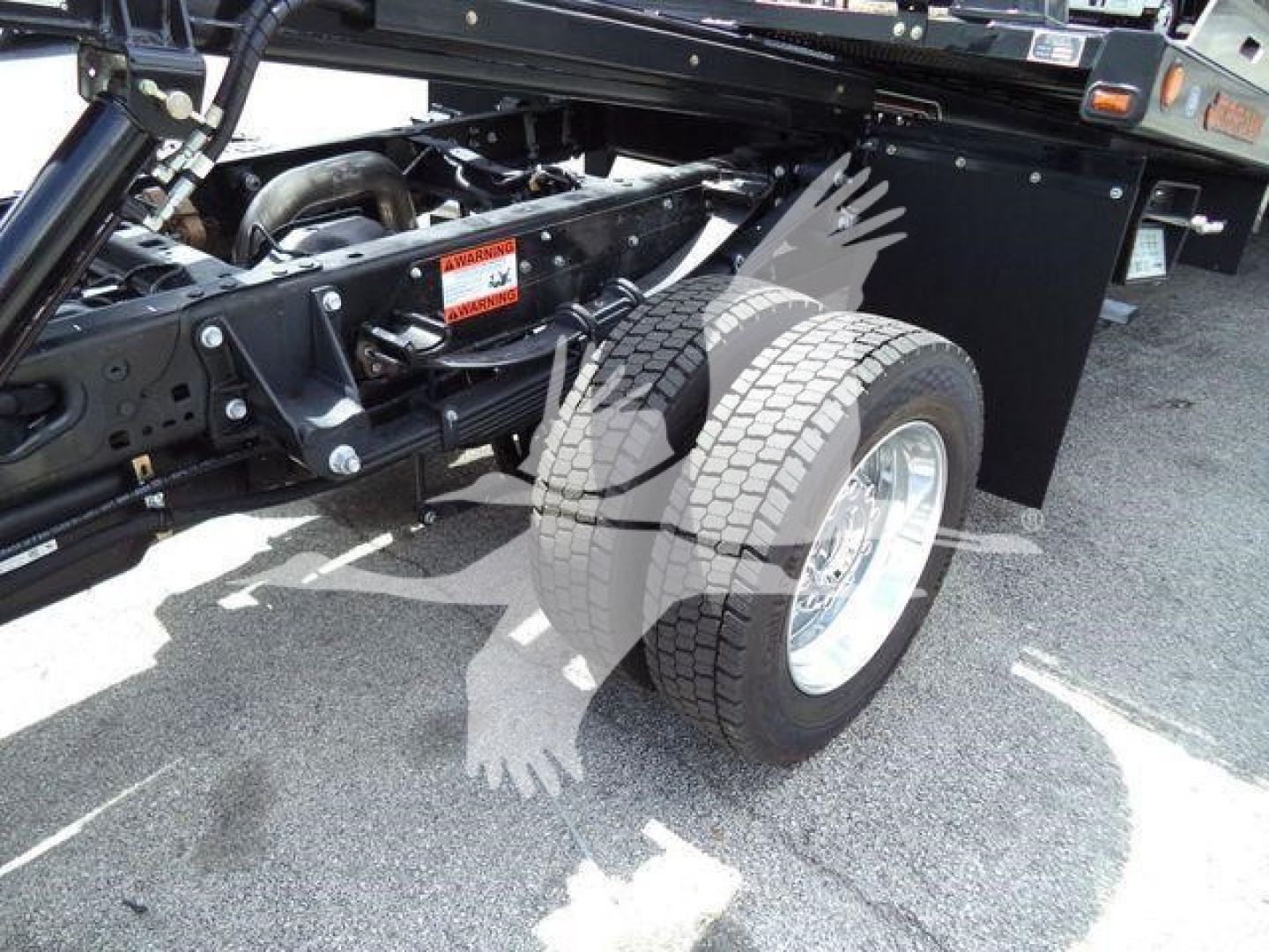 Truck chassis and dual rear wheels of a Ford F-550 rollback vehicle showing suspension and tire detail.
