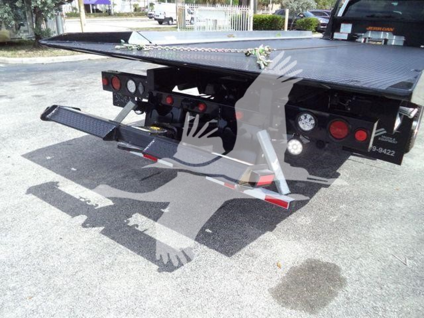 Rear of a 2024 Ford F550 rollback flatbed truck showing hydraulic system and rear bumper with lights