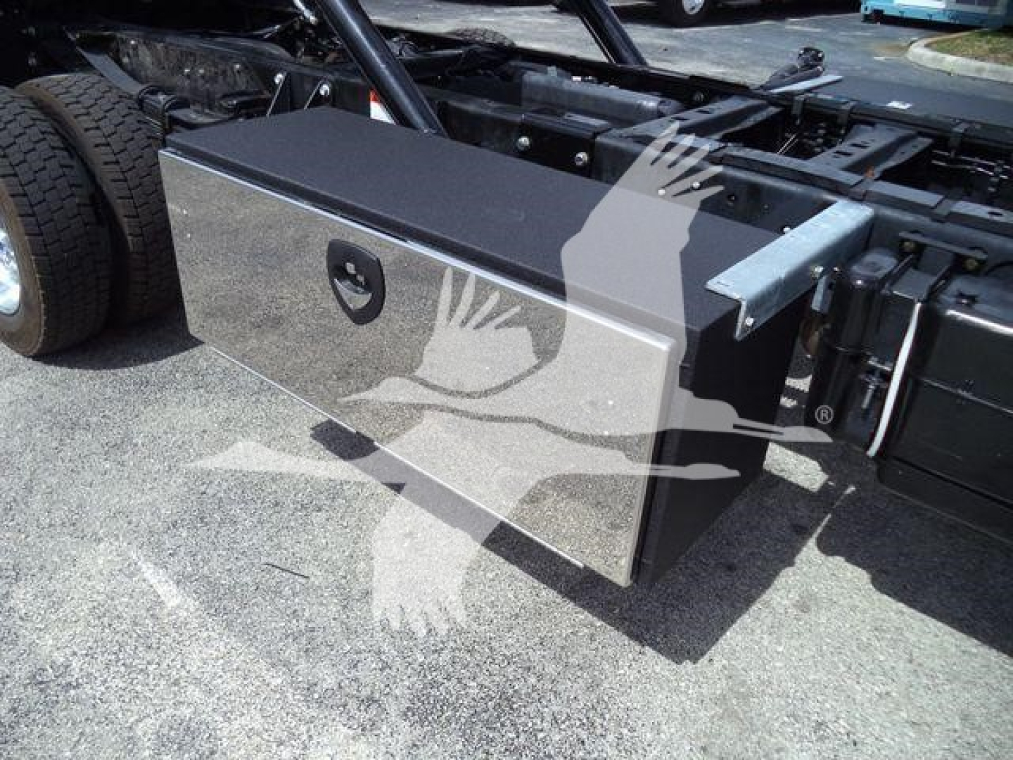 Truck rear chassis with a large black tool/storage box mounted on side, undercarriage, dual rear wheels visible.