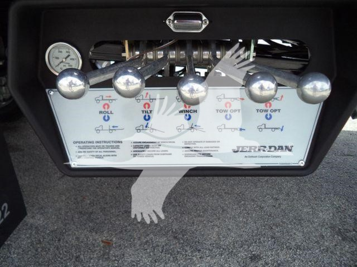 Panel of JERR-DAN rollback tow truck showing control levers with labels: ROLL, TILT, WING, TOW OUT, TOW IN, plus instructions and a JERR-DAN logo.