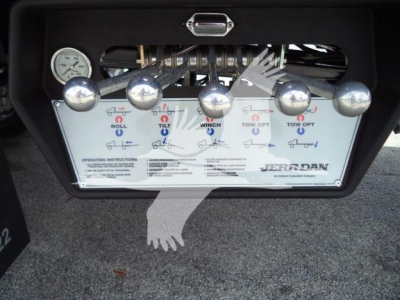 Panel of JERR-DAN rollback tow truck showing control levers with labels: ROLL, TILT, WING, TOW OUT, TOW IN, plus instructions and a JERR-DAN logo.