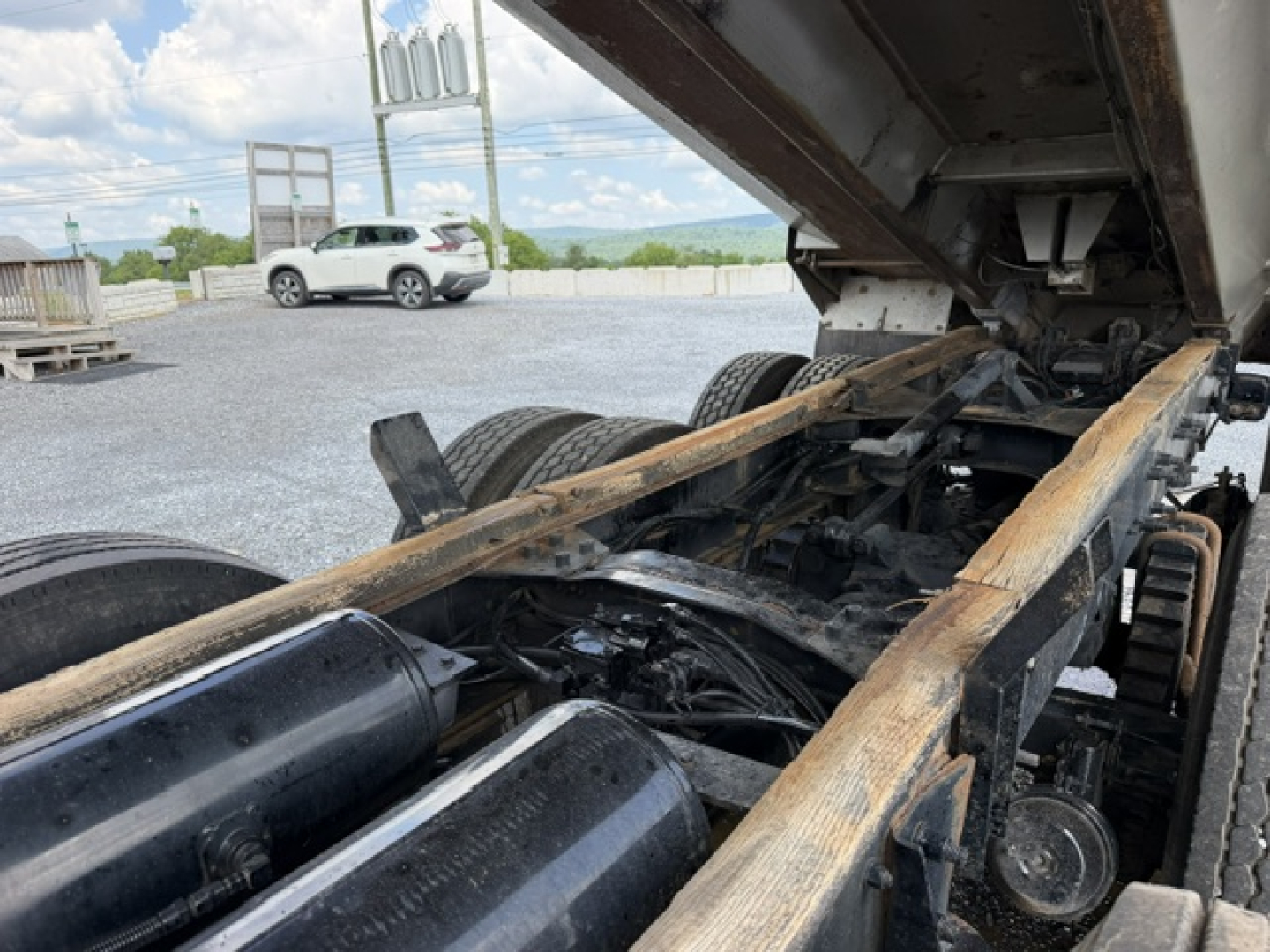 Chassis view of a 2004 Mack CV713 dump truck showing frame rails, drive axles, and underbody components with raised dump bed.