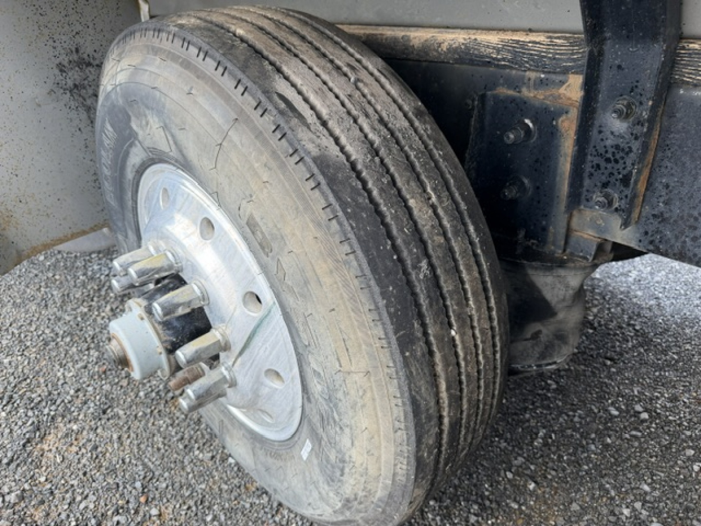 Front dual rear wheel of a 2004 Mack CV713 dump truck showing a dual-tire setup with hub, lug nuts, and part of the frame; no text visible.