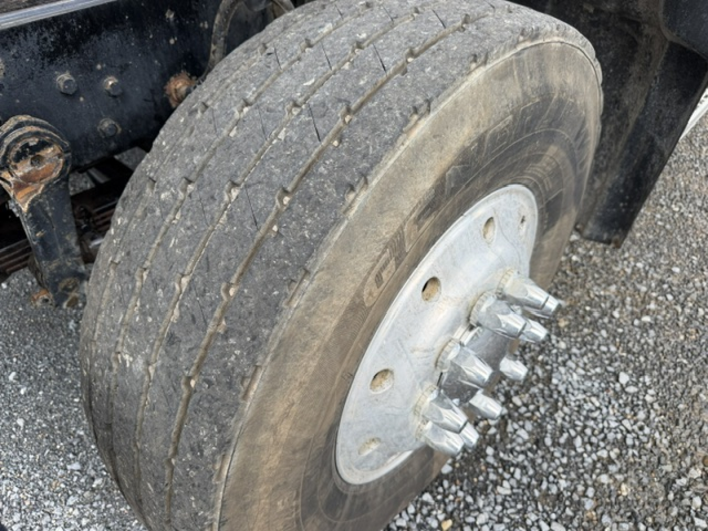 Wheel and hub of a Mack CV713 dump truck showing a multi-lug steel wheel and tire mounted on a drum hub.