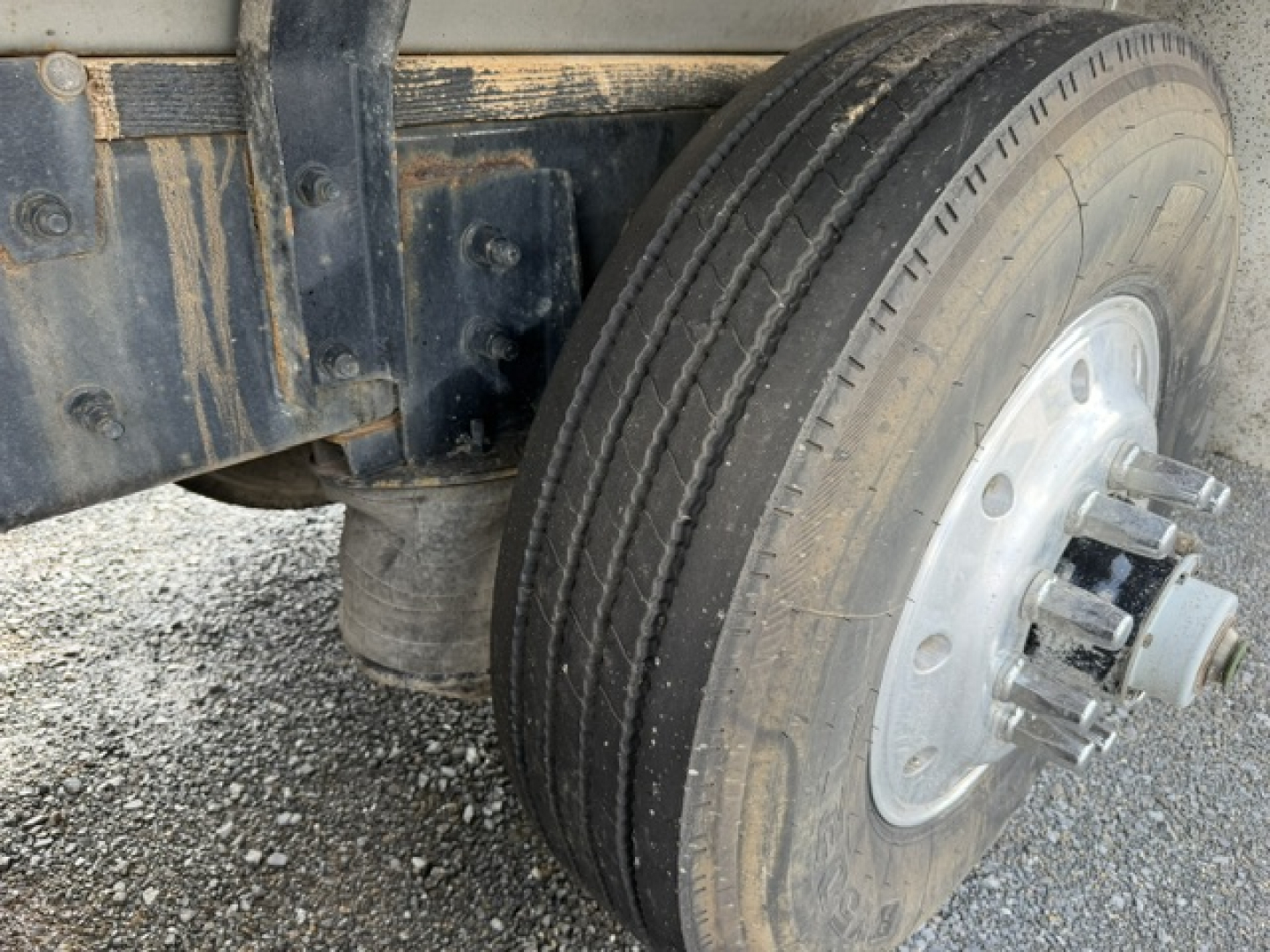 Mack CV713 truck wheel and suspension view showing dual rear dual wheels and tire tread with metal hub cover.