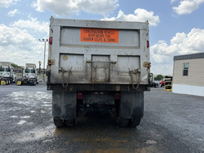 Dump truck bed rear view showing orange safety sign and tailgate latches.