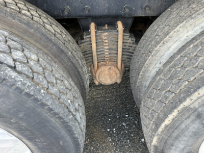 Mack CV713 dual rear tires and suspension view showing leaf spring and axle area with visible riveted components.