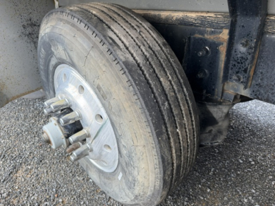 Front dual rear wheel of a 2004 Mack CV713 dump truck showing a dual-tire setup with hub, lug nuts, and part of the frame; no text visible.