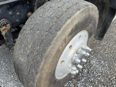 Wheel and hub of a Mack CV713 dump truck showing a multi-lug steel wheel and tire mounted on a drum hub.