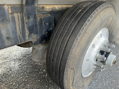 Mack CV713 truck wheel and suspension view showing dual rear dual wheels and tire tread with metal hub cover.
