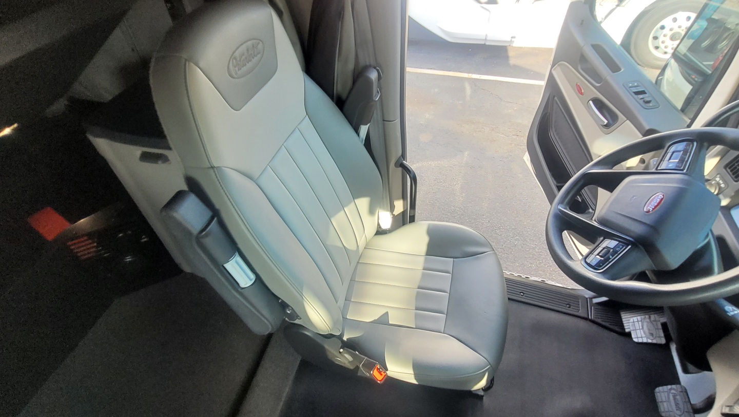 Truck cab interior showing driver seat and steering wheel of a 2025 Peterbilt 579 conventional sleeper.