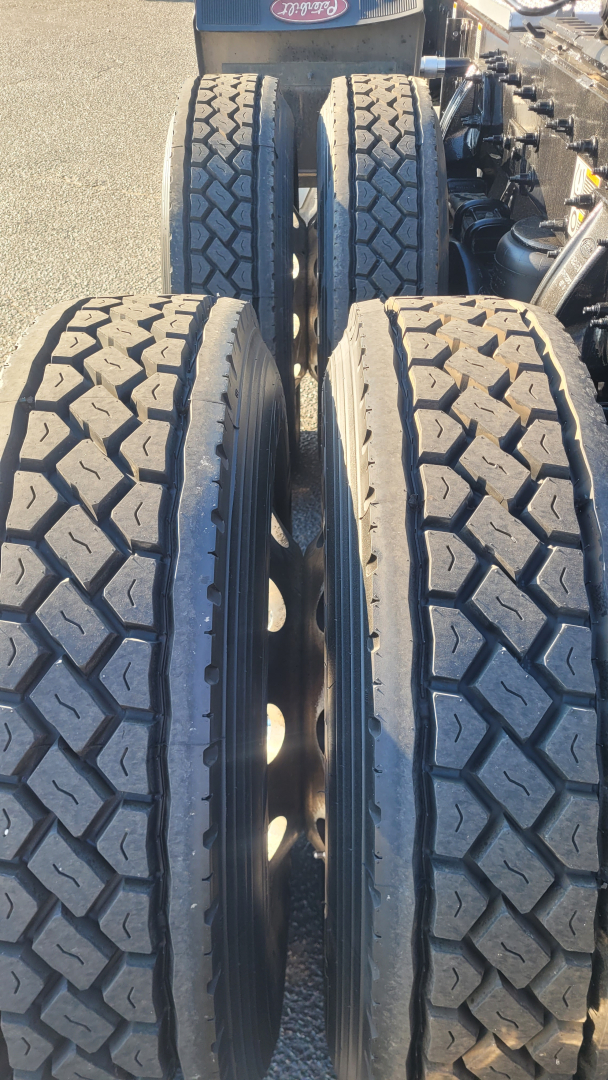 Peterbilt truck chassis showing dual rear axles with four large tires and textured tread.