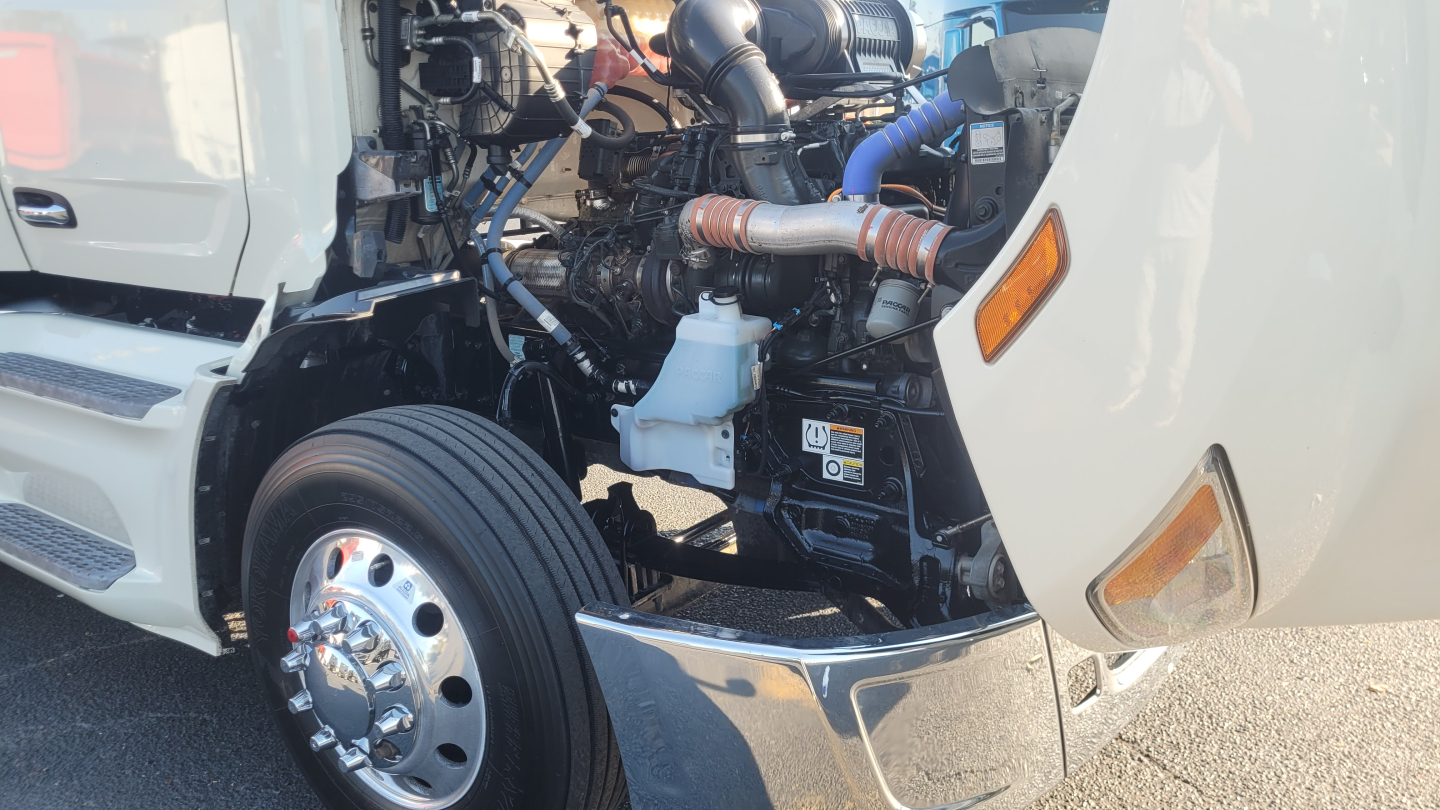 Peterbilt 579 engine bay view showing intricate hoses and components next to front wheel and cab entry panel.