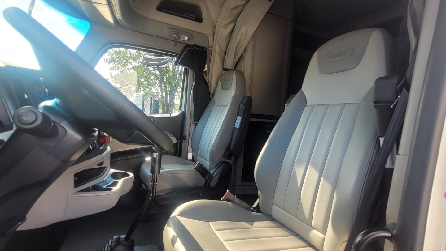 Peterbilt 579 truck interior showing driver and passenger seats with light gray upholstery.