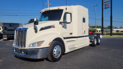 Peterbilt 579 conventional sleeper truck in white, front-left view showing cab with aerodynamic mirrors and chrome bumper.