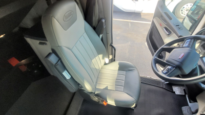 Truck cab interior showing driver seat and steering wheel of a 2025 Peterbilt 579 conventional sleeper.