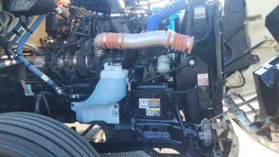 Peterbilt 579 engine bay showing coolant reservoir, turbo lines, hoses, and engine components.