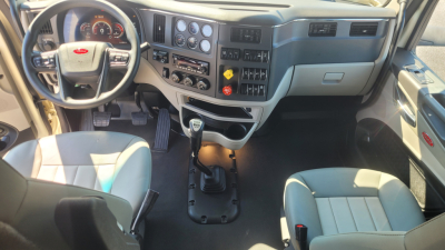 Peterbilt 579 interior showing steering wheel, dashboard with gauges, center console with gear shifter, and dual front seats.