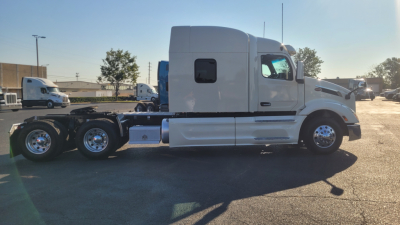 Peterbilt 579 tractor side view showing sleeper cab, 6x4 drivetrain, white exterior, aluminum fuel tanks, and dual rear axles.