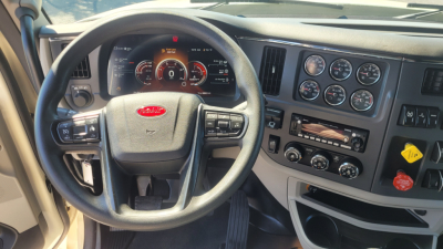 Peterbilt 579 cab interior showing steering wheel and instrument cluster with gauges and dashboard controls.