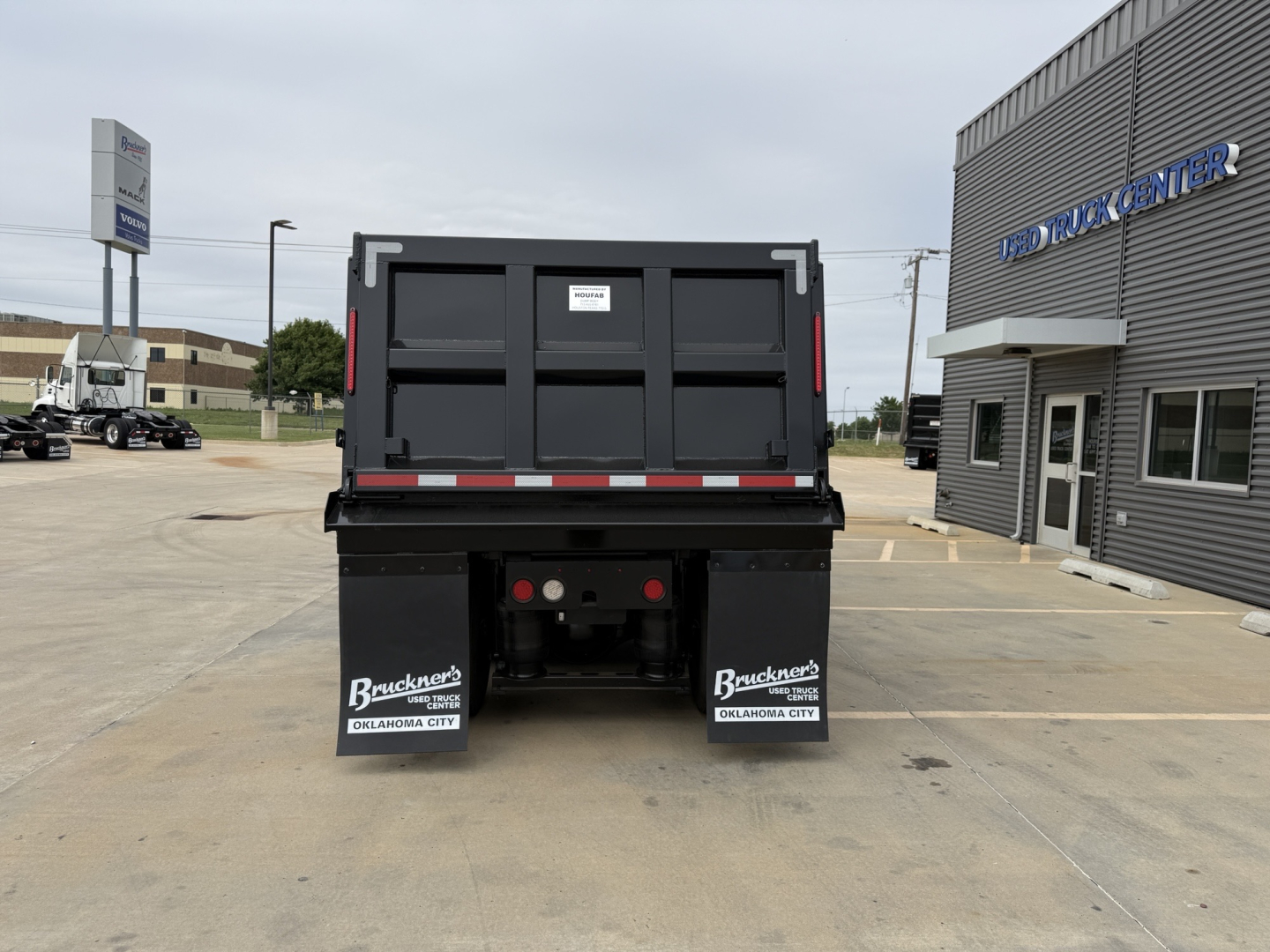 Dump truck bed rear view showing tailgate and mud flaps with Buckner's Oklahoma City logos.