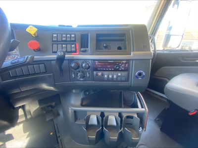 Dash area of a Volvo VNL300 interior showing switches, gear selector, climate controls, cup holders, and storage compartments
