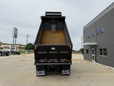 Dump truck bed of a Volvo VNL300 dump truck showing its empty steel dump box with tailgate open, in a dealership lot.