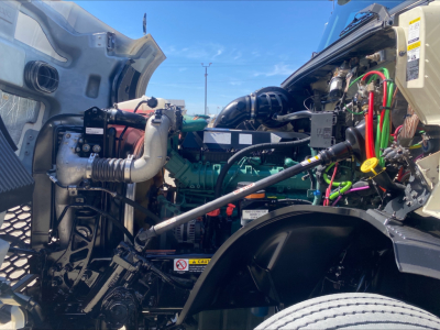 Volvo VNL300 engine bay with green engine block, hoses, wiring, and radiator visible; multiple color-coded wires and components in view.