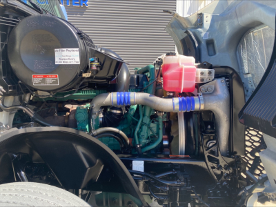 Volvo VNL300 engine bay showing coolant reservoir with pink coolant, intercooler, hoses, and engine block.