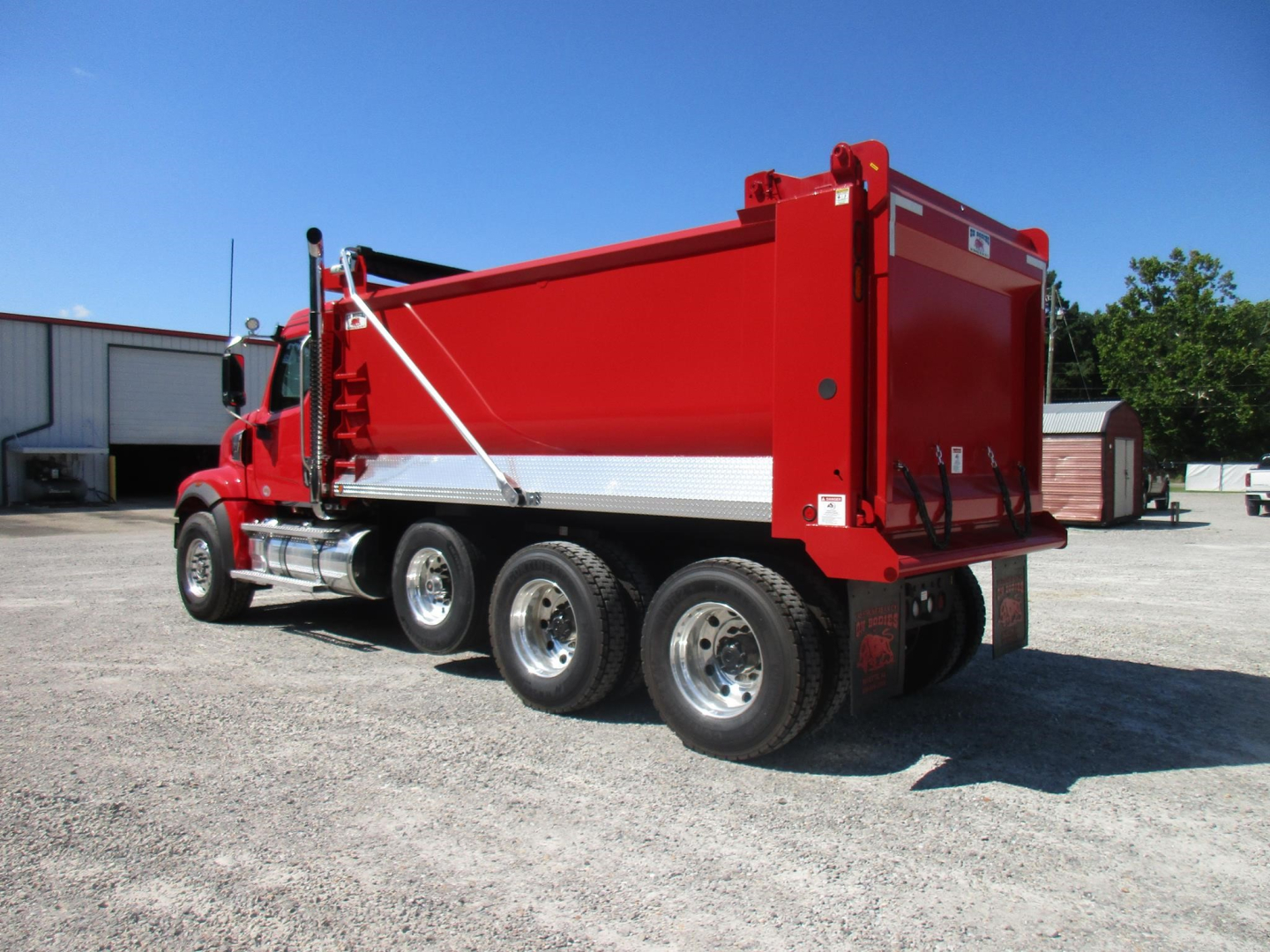 Dump truck side view showing red dump bed and triple rear wheels with chrome wheels.