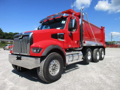 Western Star 49X dump truck in red with chrome grille and dual rear axles, side exhaust, and large dump bed visible.