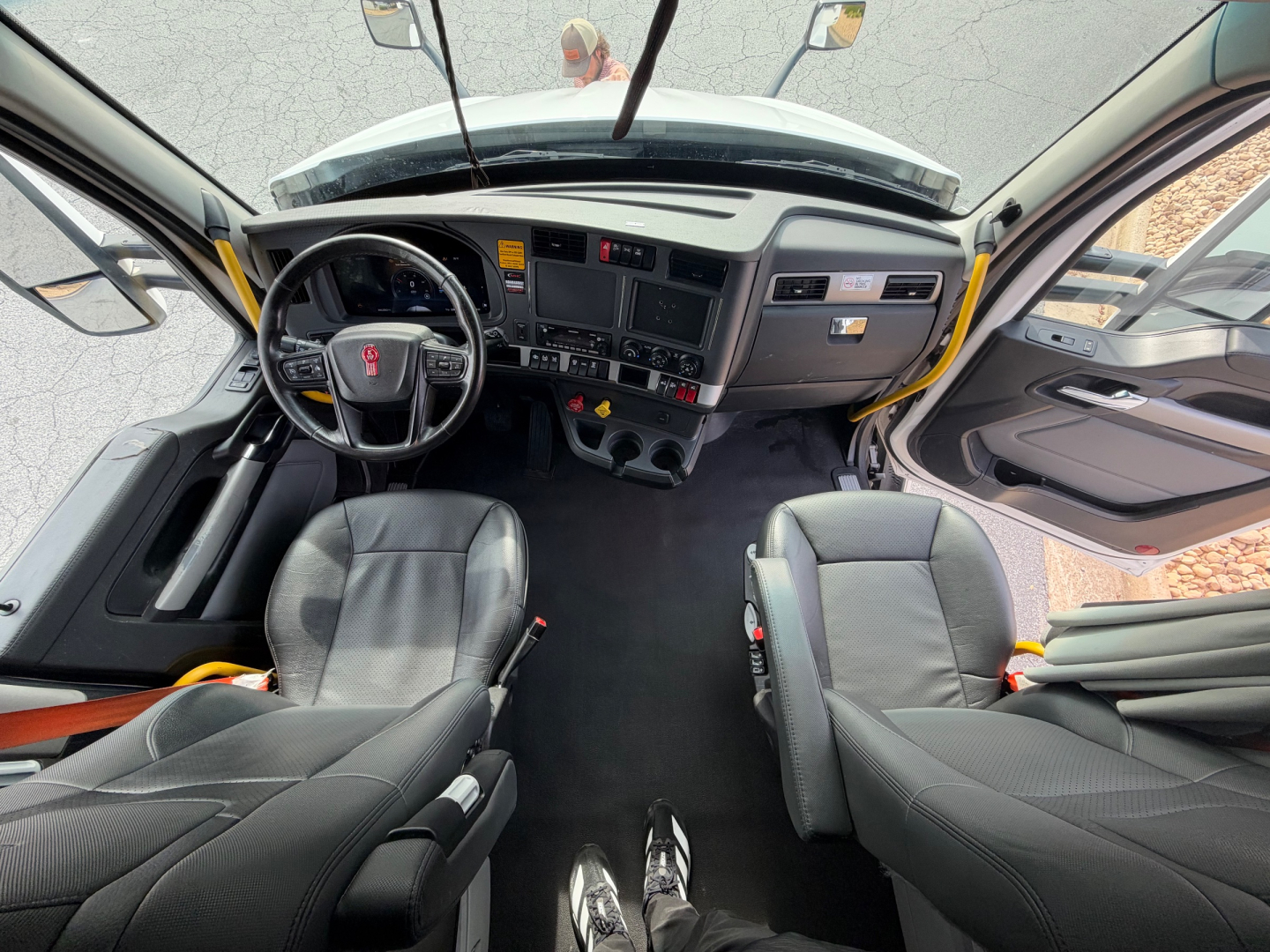 Kenworth T680 cab interior showing steering wheel, dashboard, and front seats.