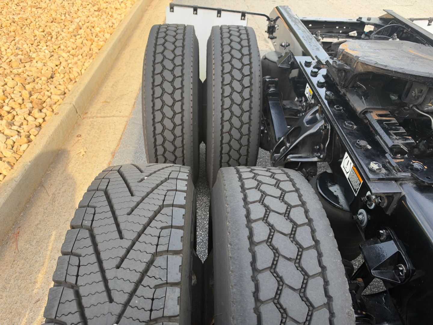 Kenworth T680 truck chassis with dual rear axles and dual tires visible, close-up of rear wheel/tire tread patterns.