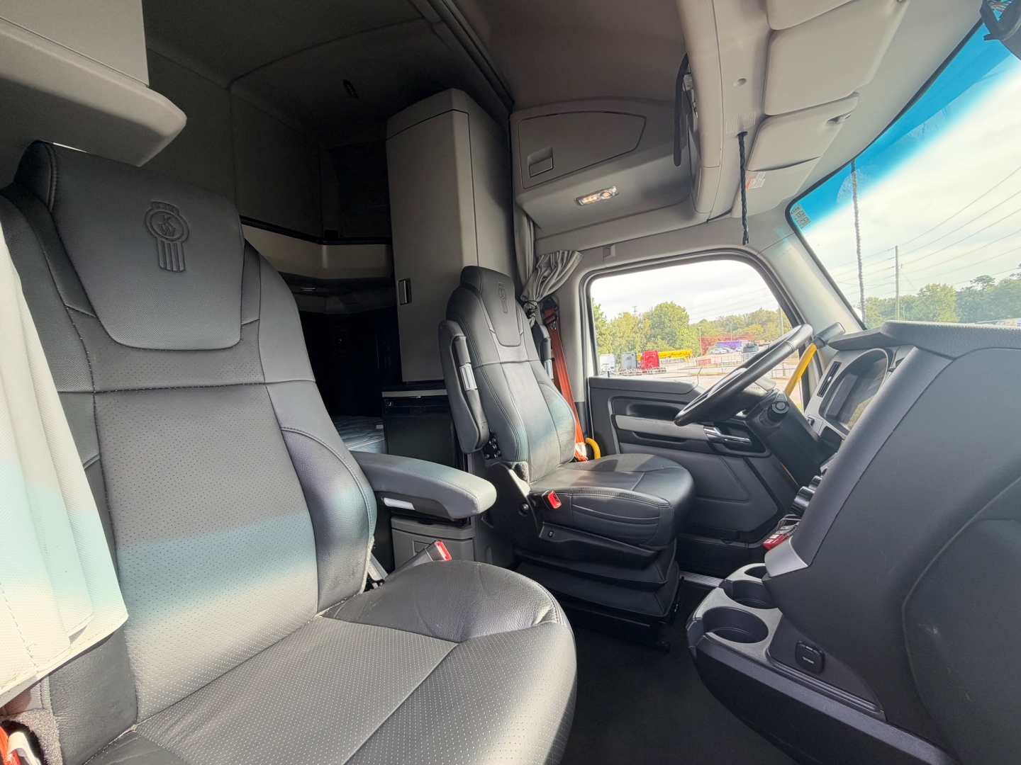 Kenworth T680 interior cab view showing driver seat and passenger seat with dashboard and sleeper area