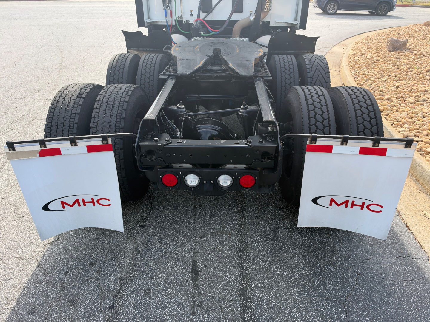 Kenworth T680 rear view showing dual rear axles and mud flaps with MHC logos