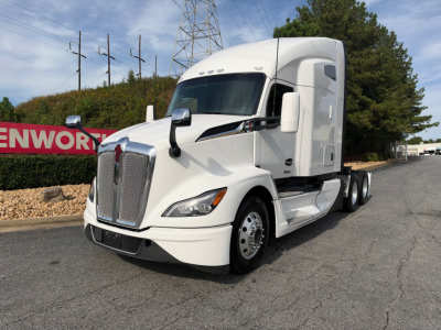 Kenworth T680 conventional sleeper tractor in white, front-left view showing cab and grille with side mirrors.